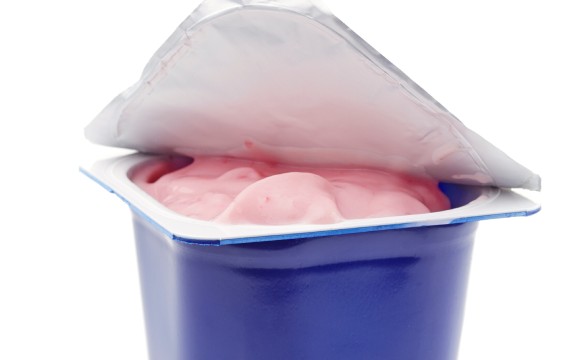 fresh pink berry yogurt in blue plastic pot on a white background
