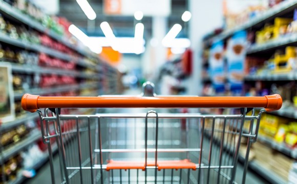 Abstract blurred photo of store with trolley in department store background. Supermarket aisle with empty red shopping cart