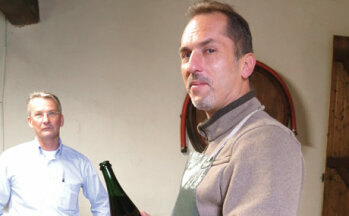 Winzer: Stéphane Vignon präsentiert eine Flasche, links Kai Haeder.