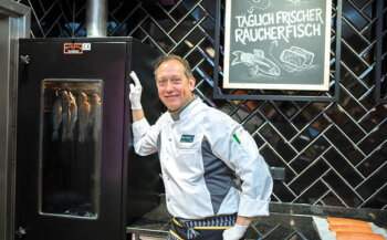 Fischfachverkäufer Karsten Lametz wacht darüber, dass der Räucherfisch aus dem neuen Ofen lecker schmeckt.