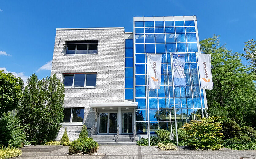 Mondi-Gebäude mit Glasfassade und Firmenfahnen vor dem Eingang.