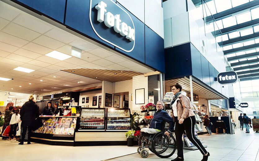 Neuausrichtung Fotex: Auf dem Foto sieht man eine Fotex Filiale in einem Einkaufszentrum. Zwei Personen, eine im Rollstuhl, betreten den Laden.