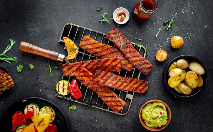 Billie Green nun eigenständig: auf Grill liegen Fleischstücke und Paprika; daneben Schälchen mit Marinade, Kartoffeln und Gemüse.o