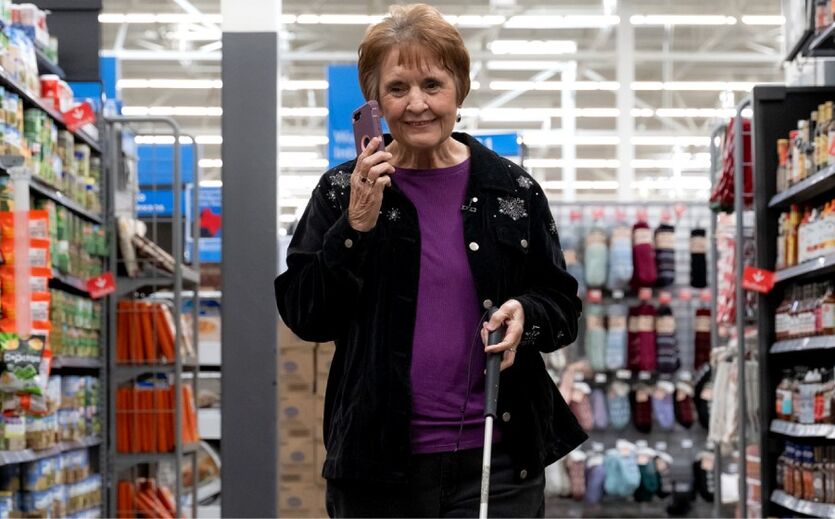 Digitale Einkaufshilfe für Blinde bei Walmart: Zu sehen ist eine alte Dame mit Smartphone und Blindenstock in einem Supermarktgang. 