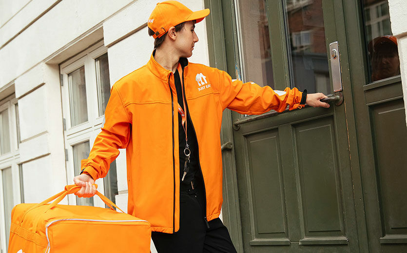 Ein Just-Eat-Takeaway-Lieferfahrer betritt ein Gebäude.