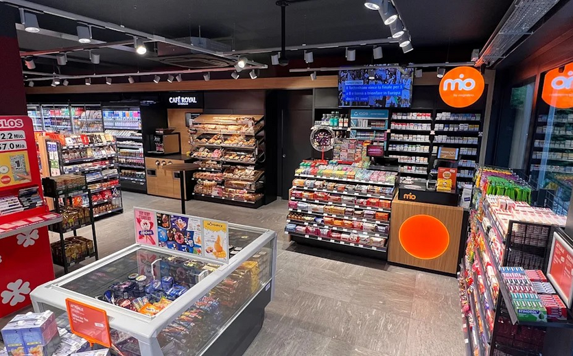 Innenansicht eines modernen mio-Shops mit Regalen voller Snacks, Getränken und Alltagsartikeln