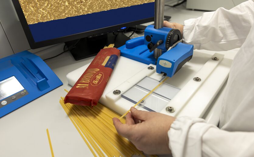 Laboraufnahme mit Barilla-Spaghetti, die von einer Fachkraft in einem Messgerät zur Oberflächenanalyse getestet werden.