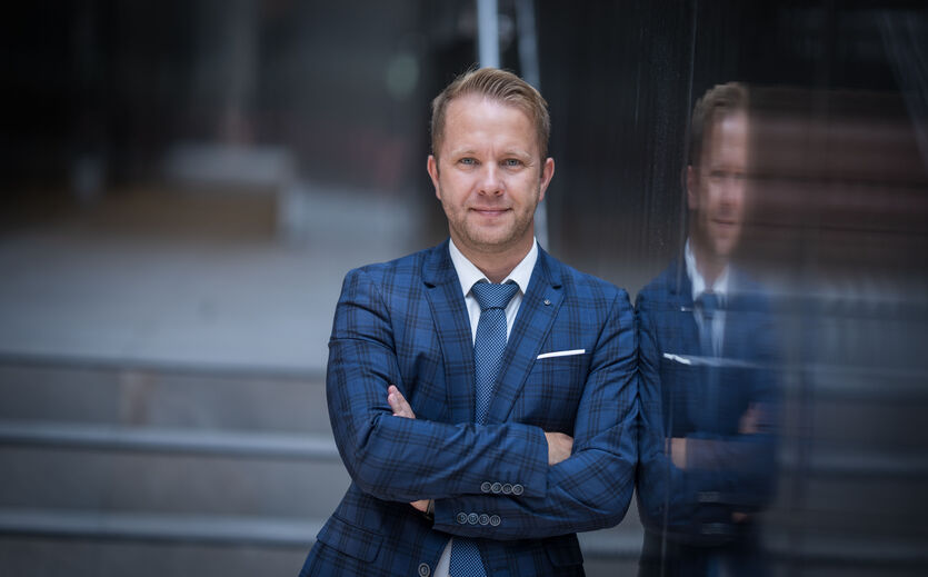 Bram Wouters im blauen Anzug vor Glasfassade.