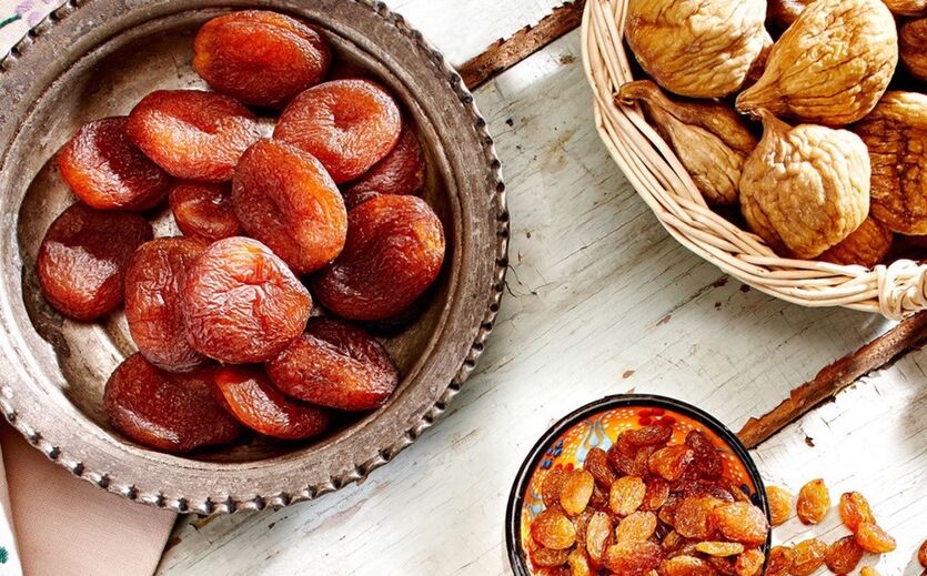 Schalen mit getrockneten Aprikosen, Feigen und Rosinen auf einem Holztisch.