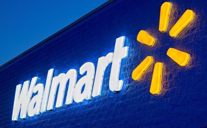 Walmart Logo an der Außenfassade eines blau beleuchteten Geschäfts.
