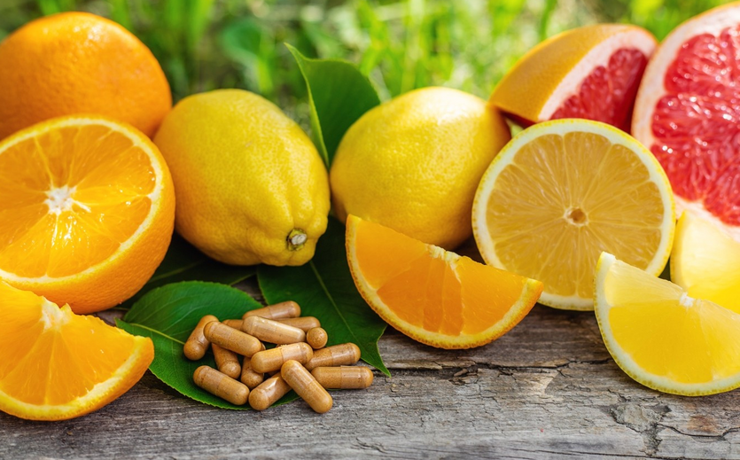 Aufgeschnittene Orangen, Zitronen und Grapefruit mit braunen Kapseln auf Holztisch.