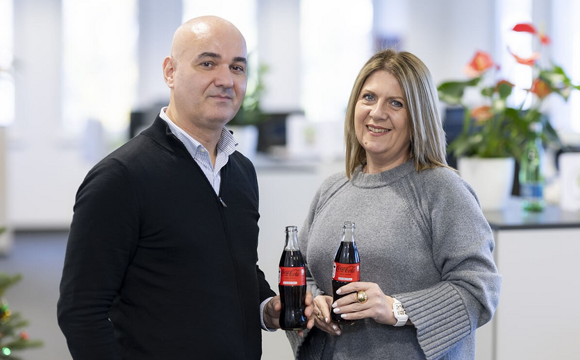 Natasa Najdanovic und Sorin Popescu halten Coca-Cola-Flaschen in einem Büro von Coca-Cola HBC Österreich.