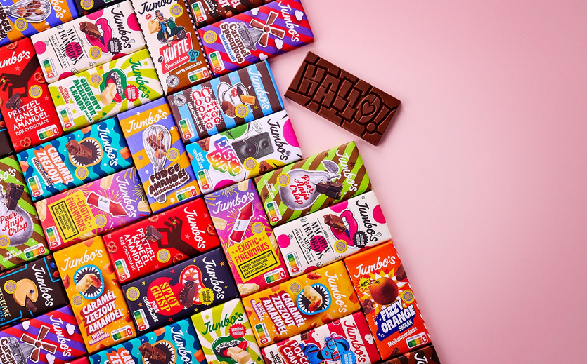 Verschiedene bunte Jumbo Schokoladentafeln liegen auf einer rosa Fläche.