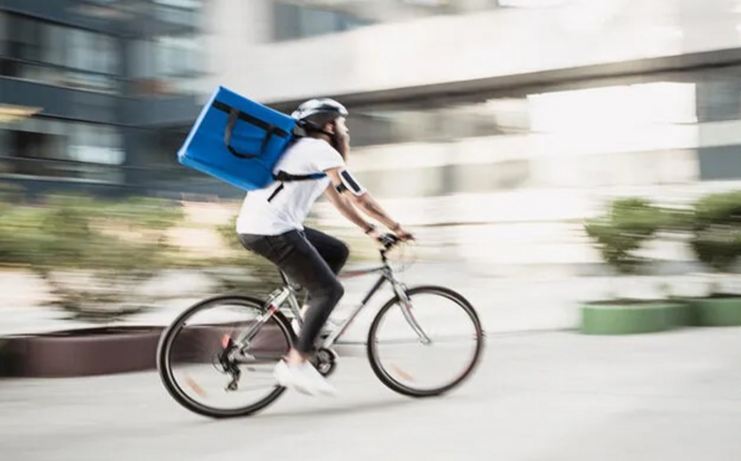 Fahrradkurier mit Lieferbox auf dem Fahrrad.