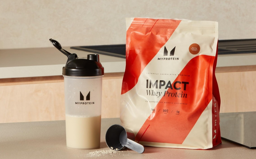 Ein Beutel Myprotein Impact Whey Protein und ein Shaker stehen auf einer Arbeitsplatte.