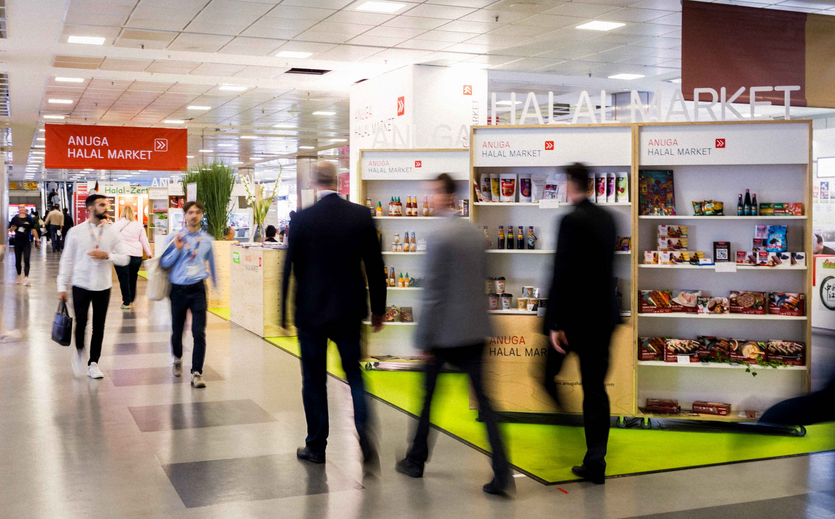 Besucherinnen auf der Anuga-Messe gehen durch eine Ausstellungshalle.