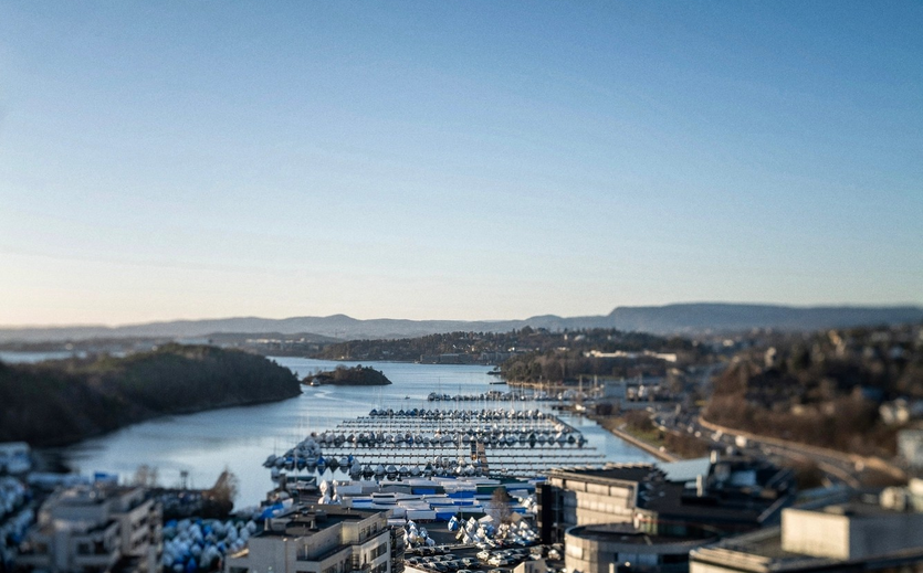 Blick auf einen Hafen in Oslo mit zahlreichen Booten und modernen Gebäuden im Vordergrund.