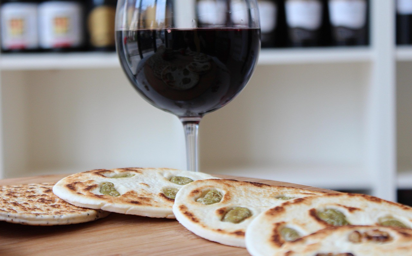 Piadina Romagnola und ein Glas Rotwein auf einem Holztisch.