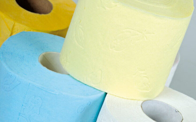 Mehrere Rollen Toilettenpapier in verschiedenen Farben übereinander gestapelt.