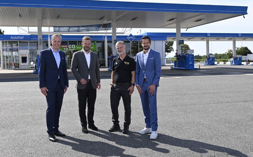 Neuer Autohof: Gruppenbild mit vier Männern vor einem Autohof..