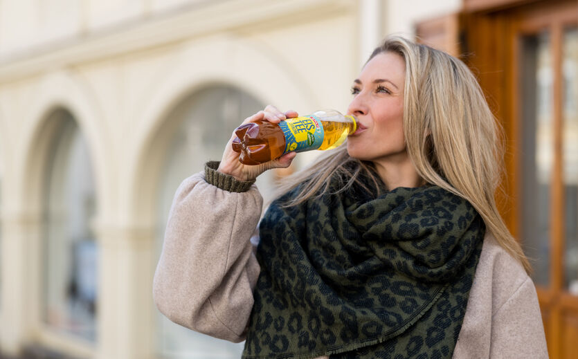 Spar spart 5.300 Tonnen Zucker bei Markenprodukten ein: Eine blonde Frau trinkt eine Flasche Eistee.