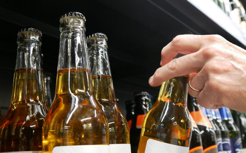 Kein Flaschenengpass: Hand greift nach Flasche in Supermarktregal.n