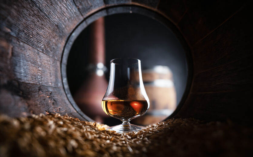 Trump kippt Zölle: Whisky-Glas steht in einem Fass.
