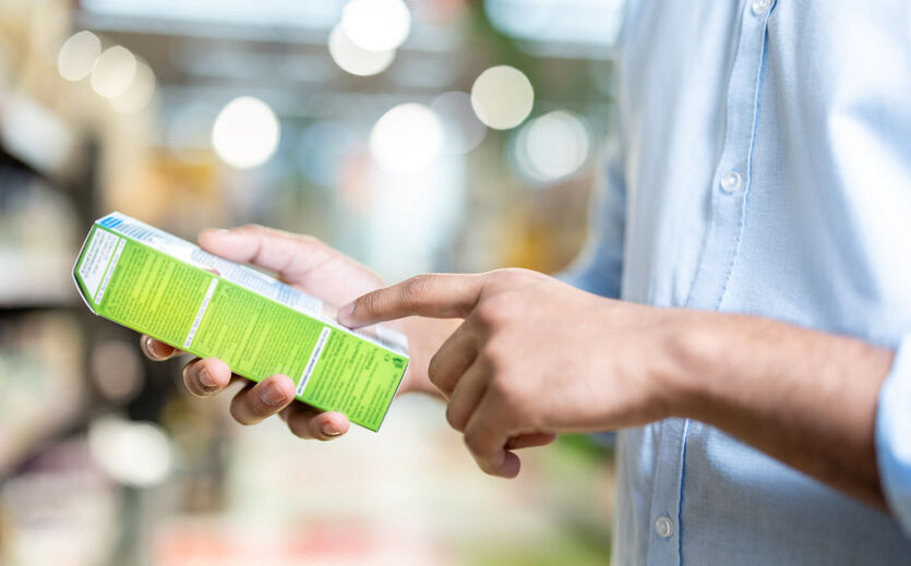 Verpackungsgesetz beschlossen: Person hält Verpackung in der Hand und liest auf ihrer Beschriftung. 